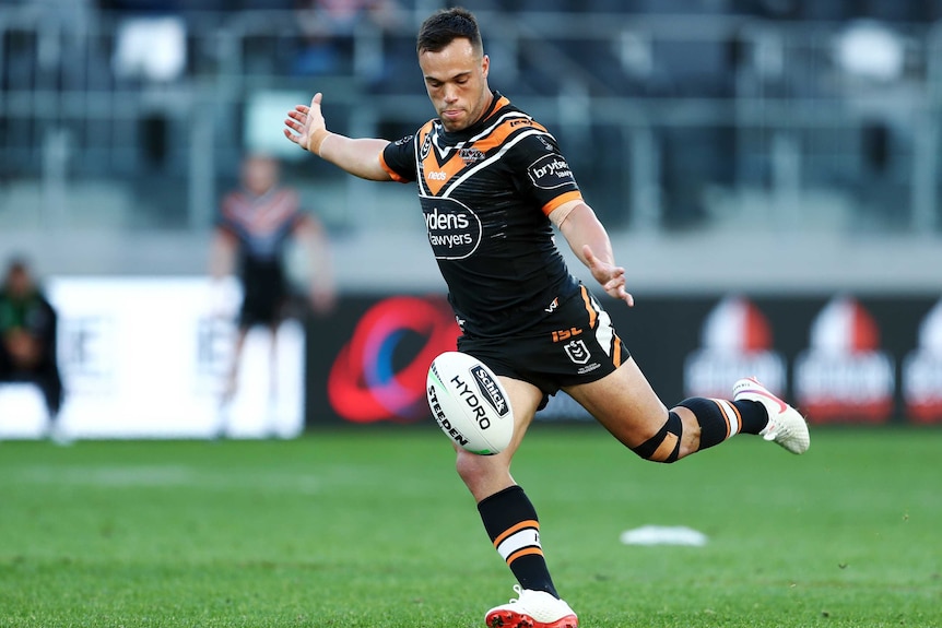 A Wests Tigers NRL player drops the ball before an attempt to kick it against the Canterbury Bulldogs.