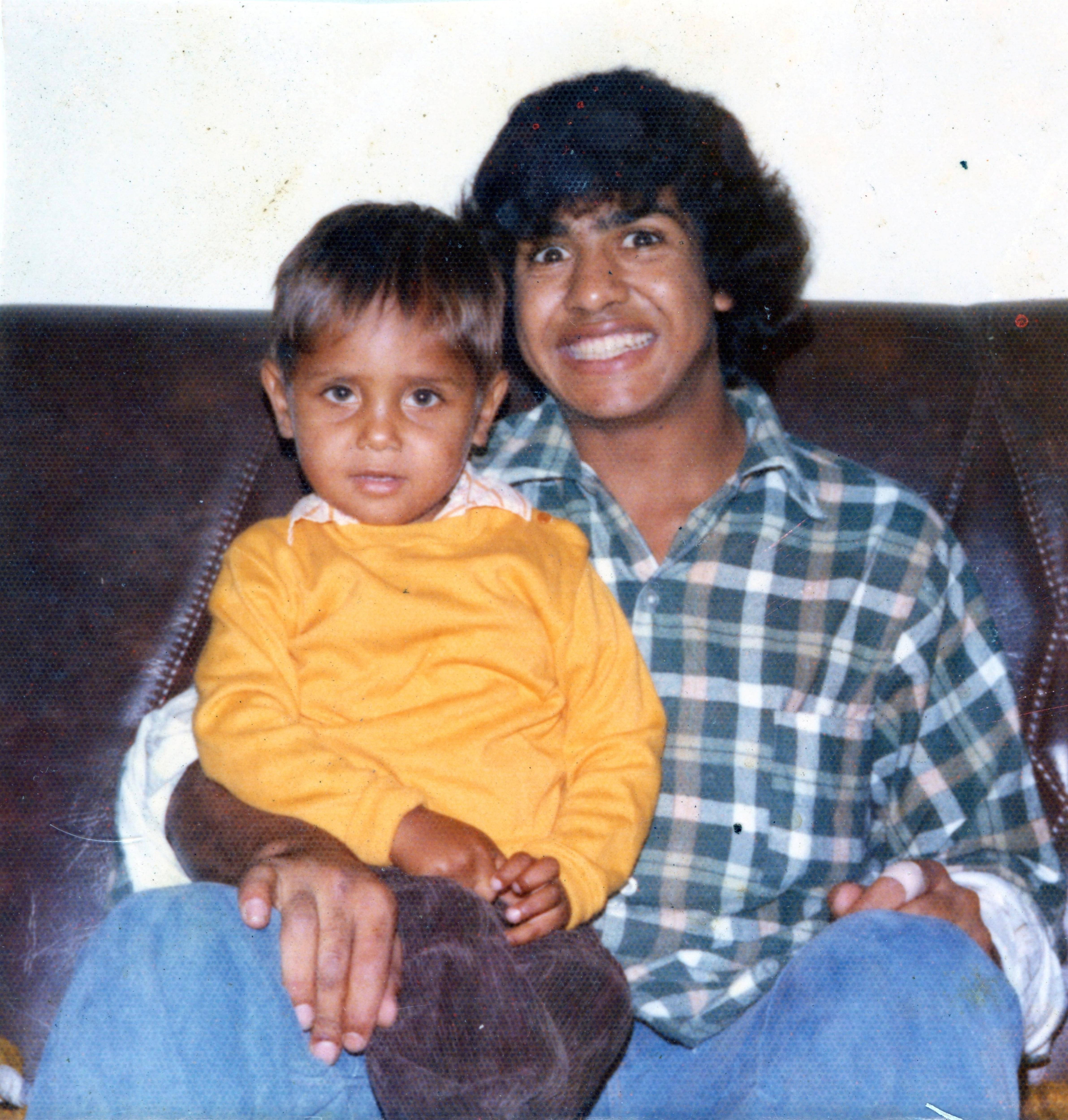 A man holding a small boy on his lap smiles towards the camera. 