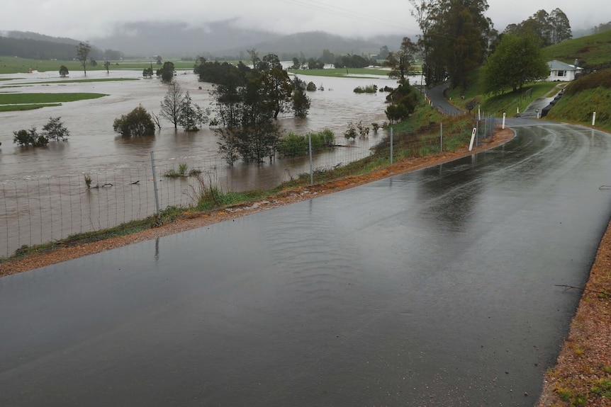 A wet road passes a completely flooded farm.