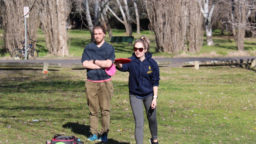 A woman throws a frisbee.