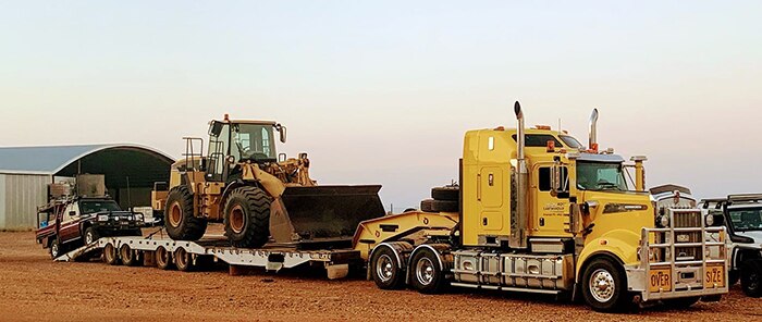 A truck carries a bulldozer bound for grazing properties in Winton.
