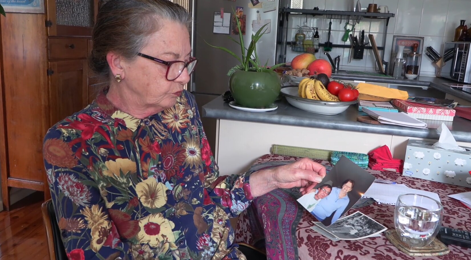 Mujer mayor con pelo gris, camisa floral y lápiz labial rojo.