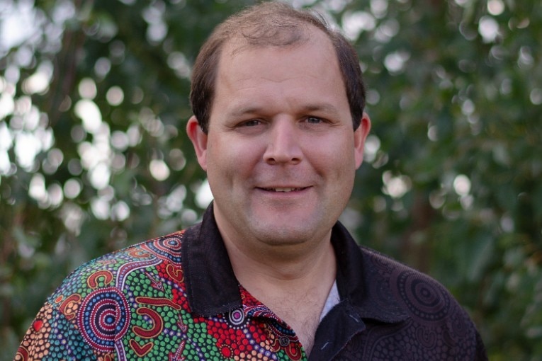 A man in a colourful polo shirt smiles at the camera