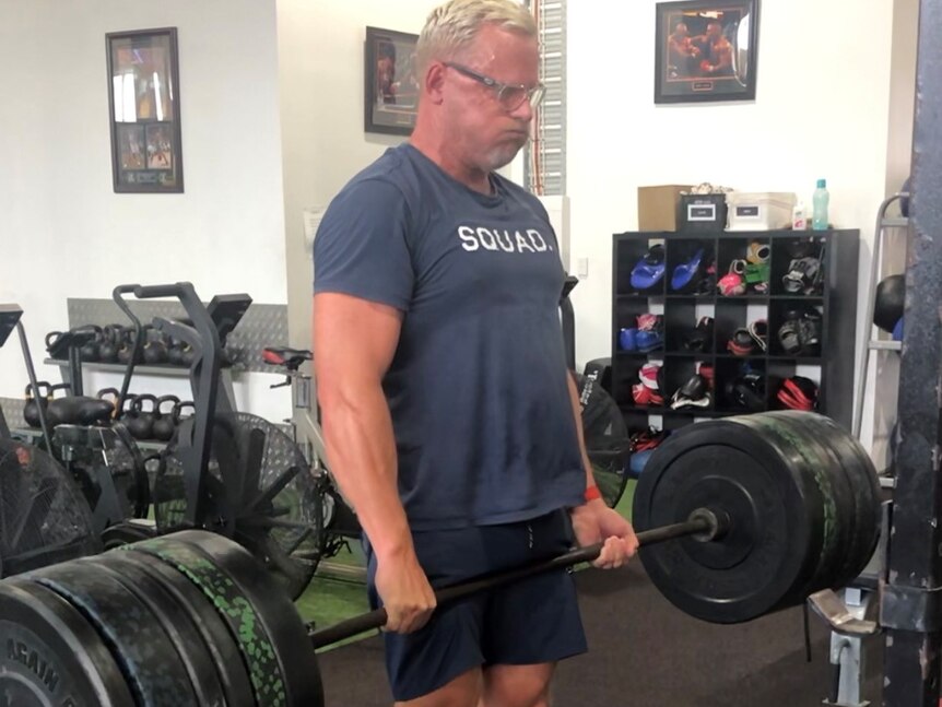 Ray at the gym, standing in a deadlift with more than 100kg on the bar