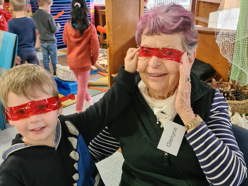 Senior female with small child and red cellophane across their eyes, smiling