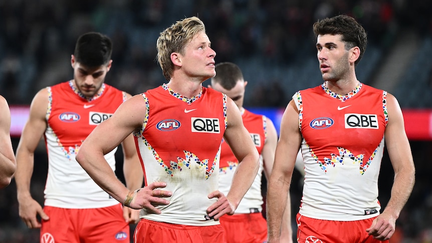 Man in dirty Sydney Swans uniform rests hands on hips 