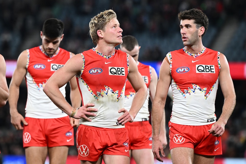 Man in dirty Sydney Swans uniform rests hands on hips 