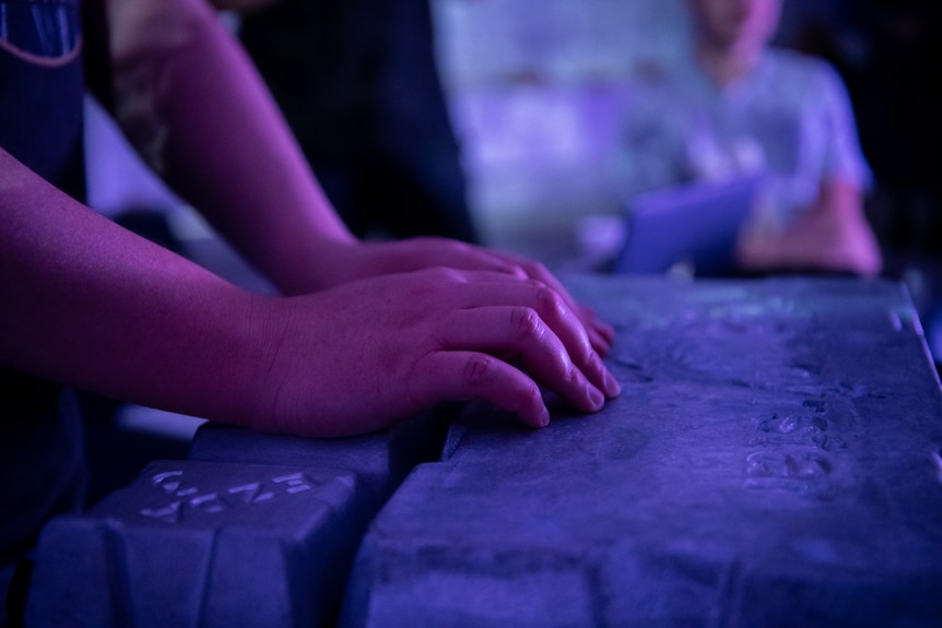 A man's hands rest on a zinc ingot