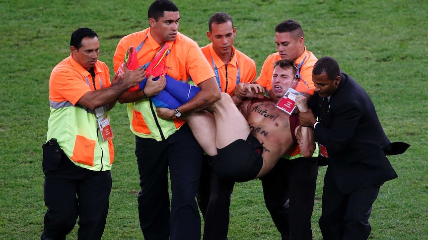 A pitch invader is carried off at the World Cup final at the Maracana.