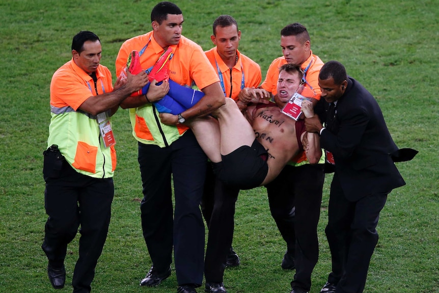 A pitch invader is carried off at the World Cup final at the Maracana.