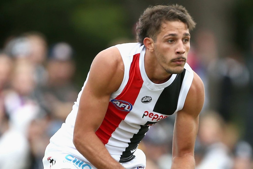 Ben Long from St Kilda runs during a match on a sunny day holding the ball.