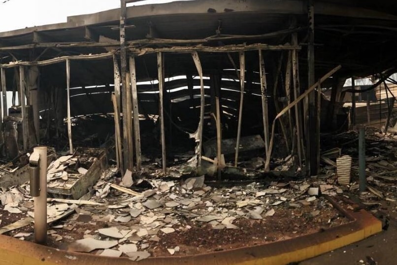 一家被烧毁的餐馆的烧焦的残骸，残骸横在地板上，建筑框架受损。