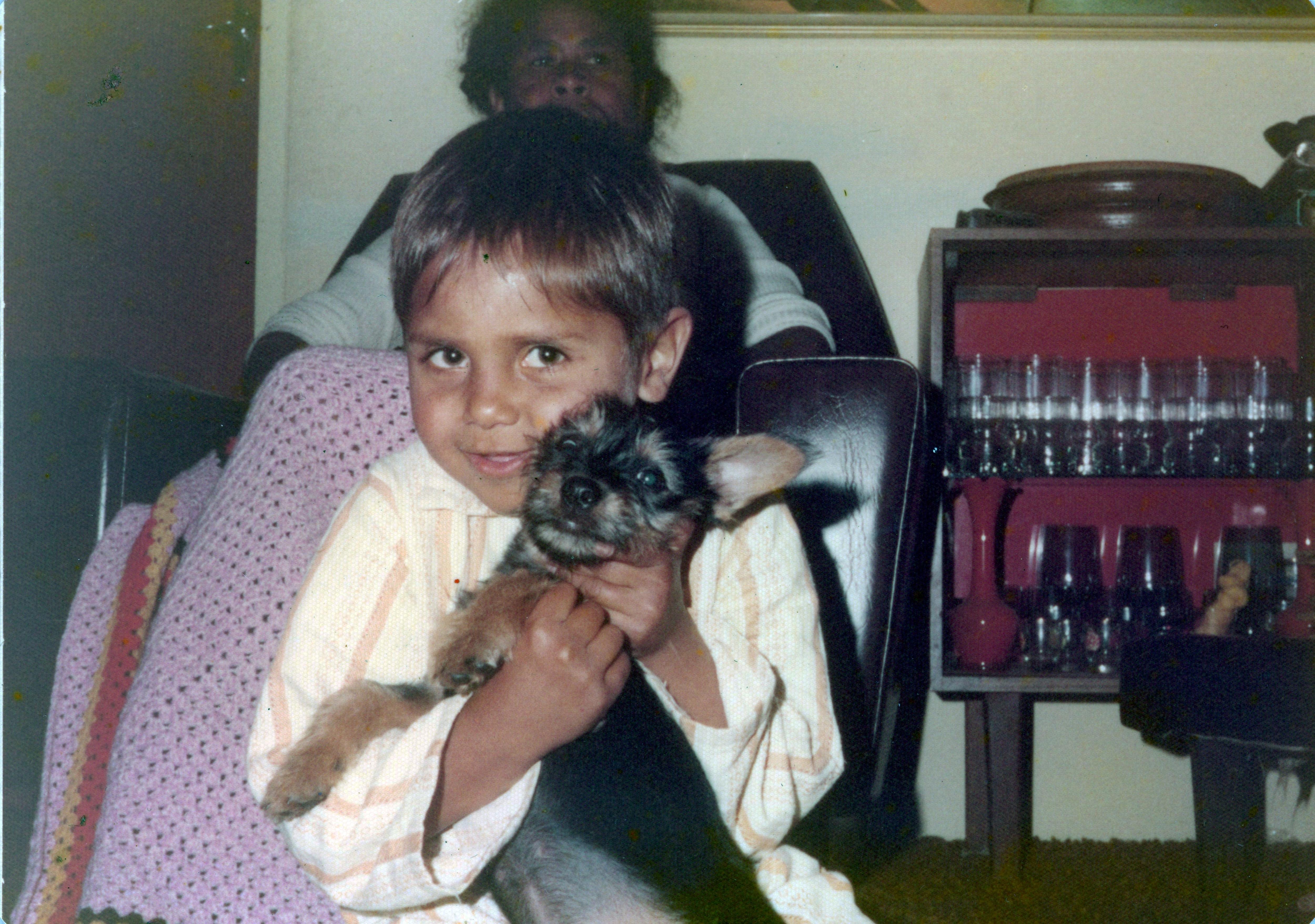 A young boy cradles a dog while smiling at the camera.