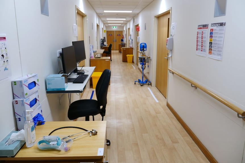 A hospital hallway cluttered with desks, computers and equipment, but no people.