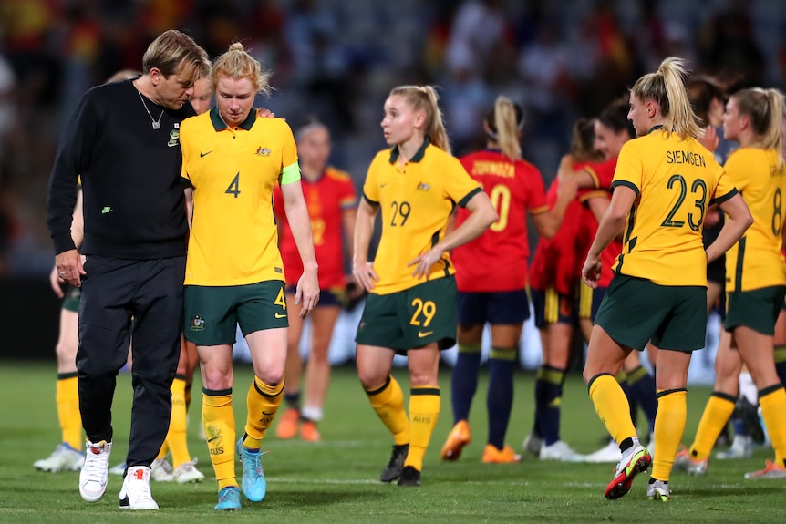 The Matildas coach puts his arm on the shoulder of dejected defender Clare Polkinghorne as he talks to her after a match.
