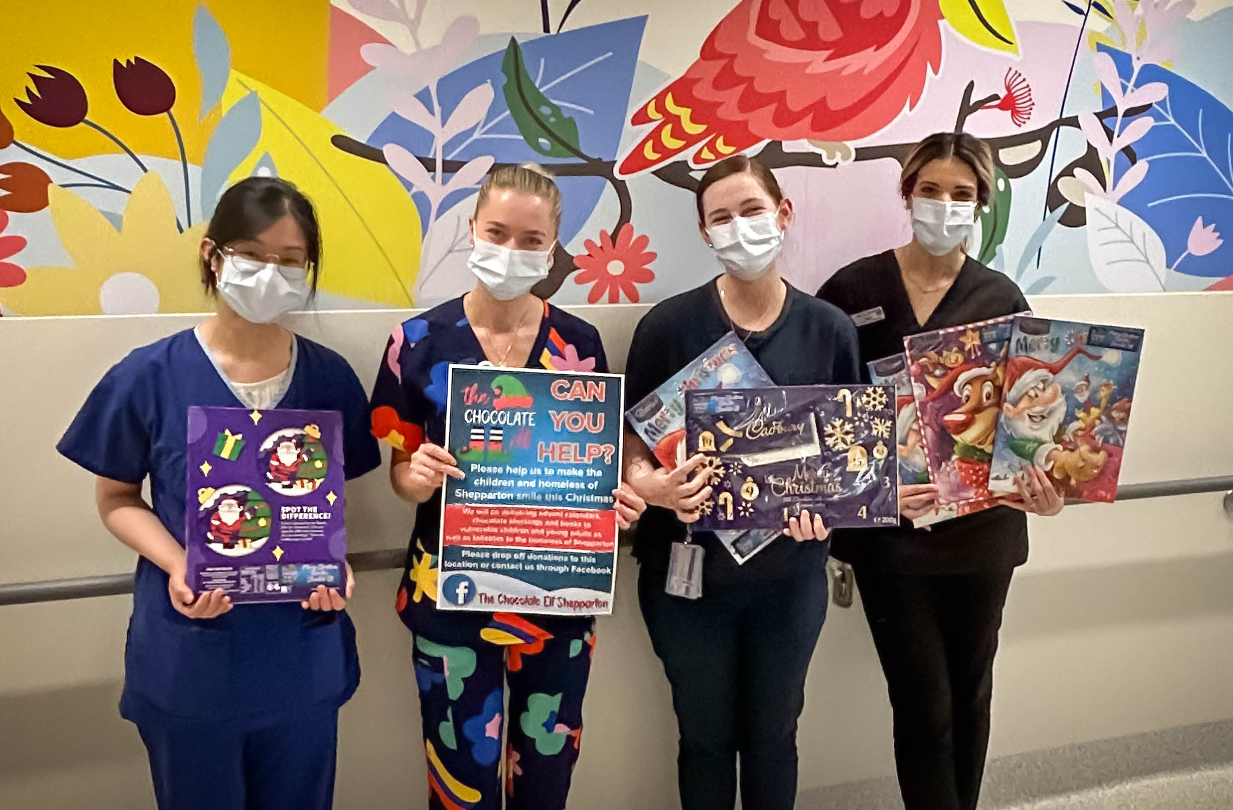 Four nurses hold advent calendars and a poster asking if you can help The Chocolate Elf