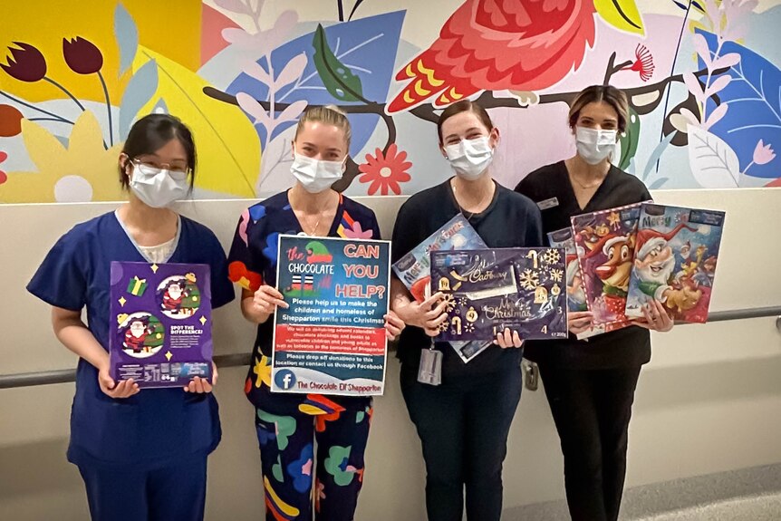 Four nurses hold advent calendars and a poster asking if you can help The Chocolate Elf
