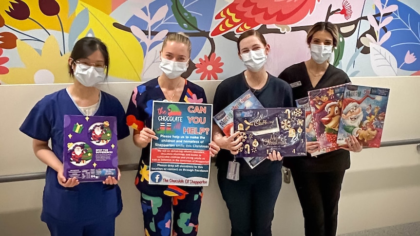 Four nurses hold advent calendars and a poster asking if you can help The Chocolate Elf