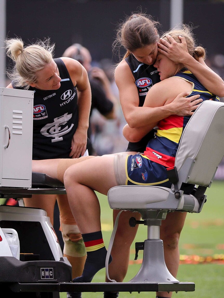 A footballer from the opposition hugs injured female footballer Chloe Scheer