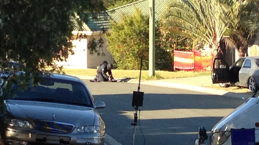 A police bomb squad officer trying to inspect a suspicious device at Redbank Plains this afternoon.