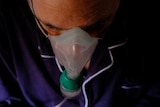 A photo looking down on a man with an oxygen mask over his mouth and nose. 
