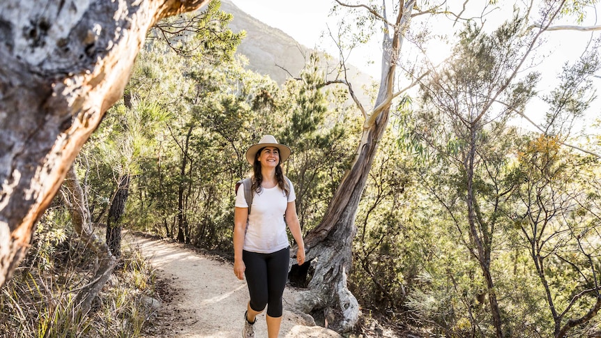 Picture of a woman wearing a hat walking down a bushy track