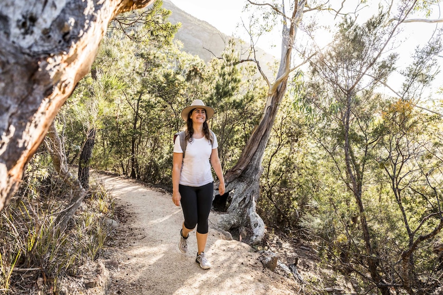 Picture of a woman wearing a hat walking down a bushy track