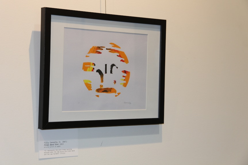 An orange and black circular painting on a white canvas, hanging in a gallery.