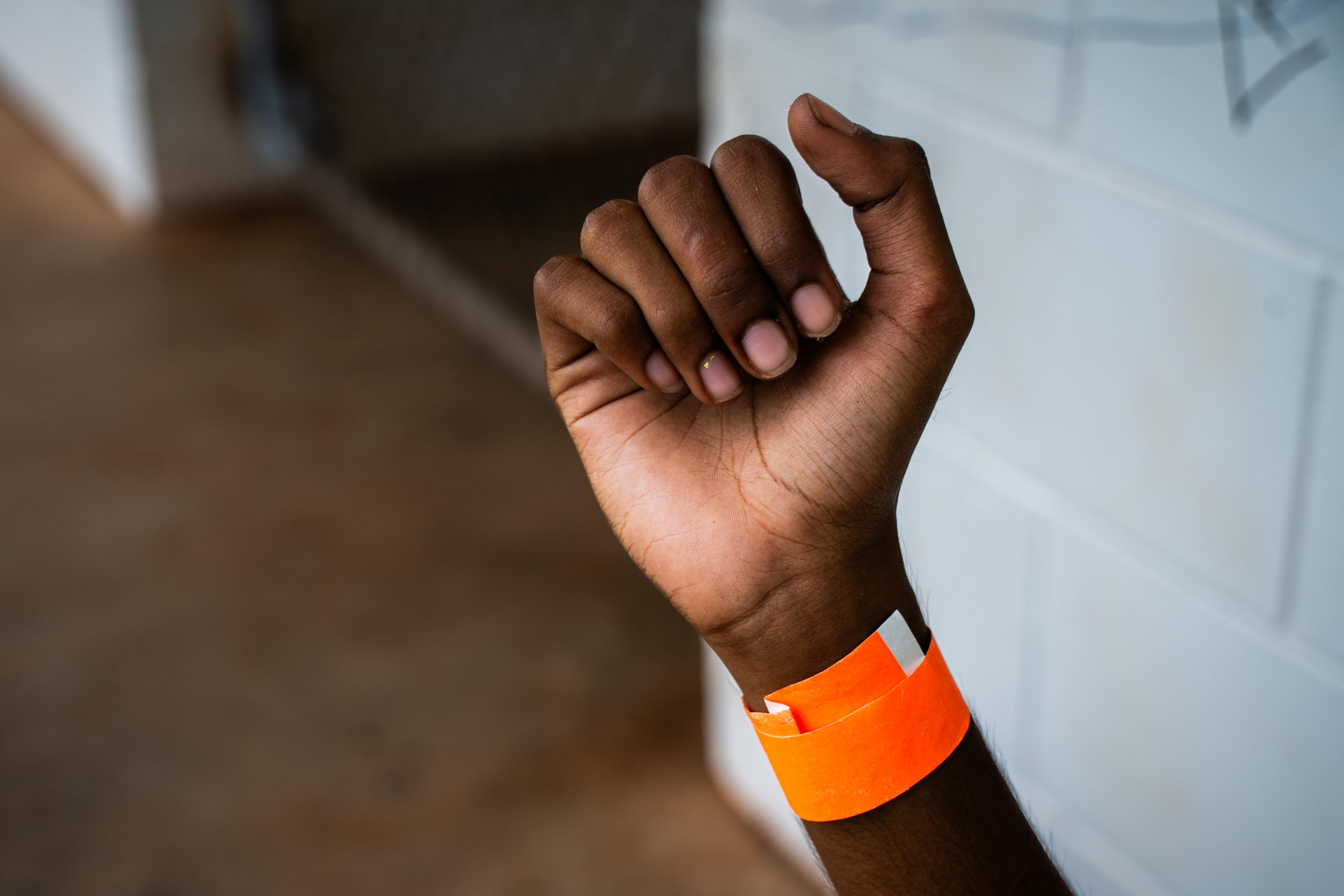 Una persona con la muñeca doblada lleva una pulsera naranja.
