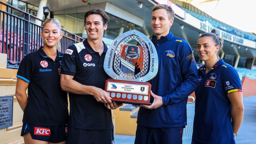 two women and two men holding a trophy at a sports stadium