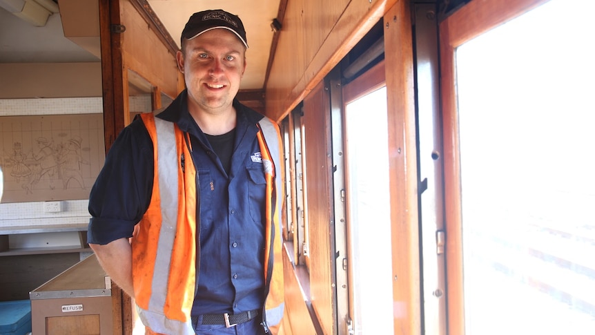 A young man stands inside a steam train