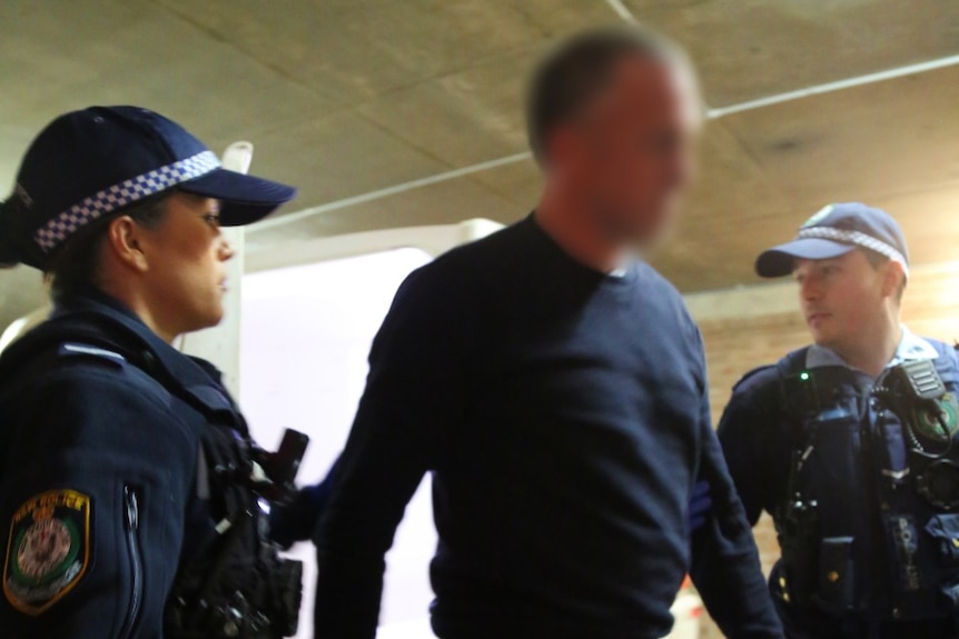 A man is lead by two police officers.