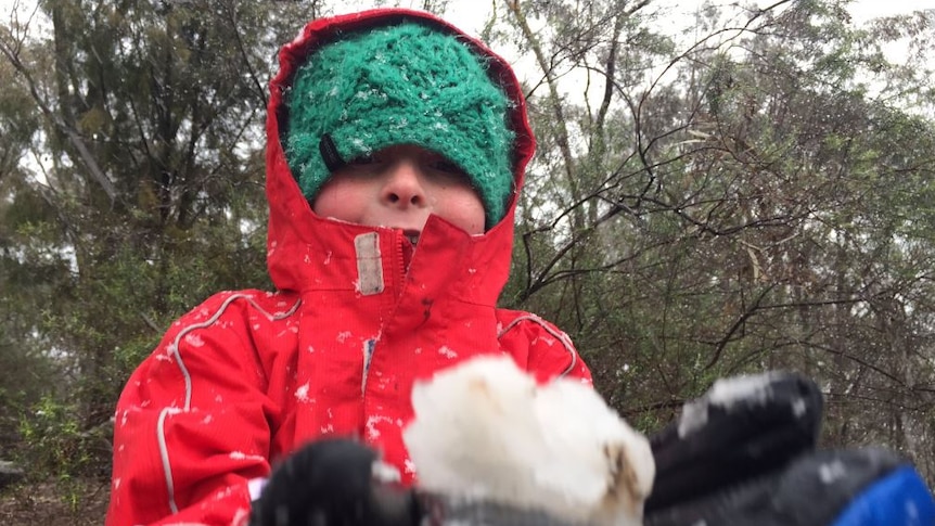 A child holds a snowball