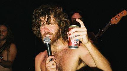 Rock singer Al Dear on stage with a can of beer.