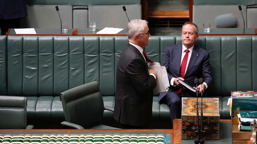 Shorten is sitting on the government benches, looking at Turnbull has he walks by.