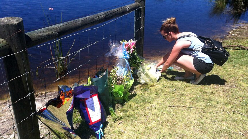 Floral tributes are laid at the lake where Sam Trott's body was found