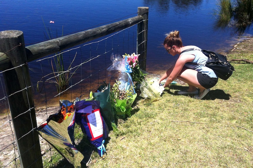 Floral tributes are laid at the lake where Sam Trott's body was found