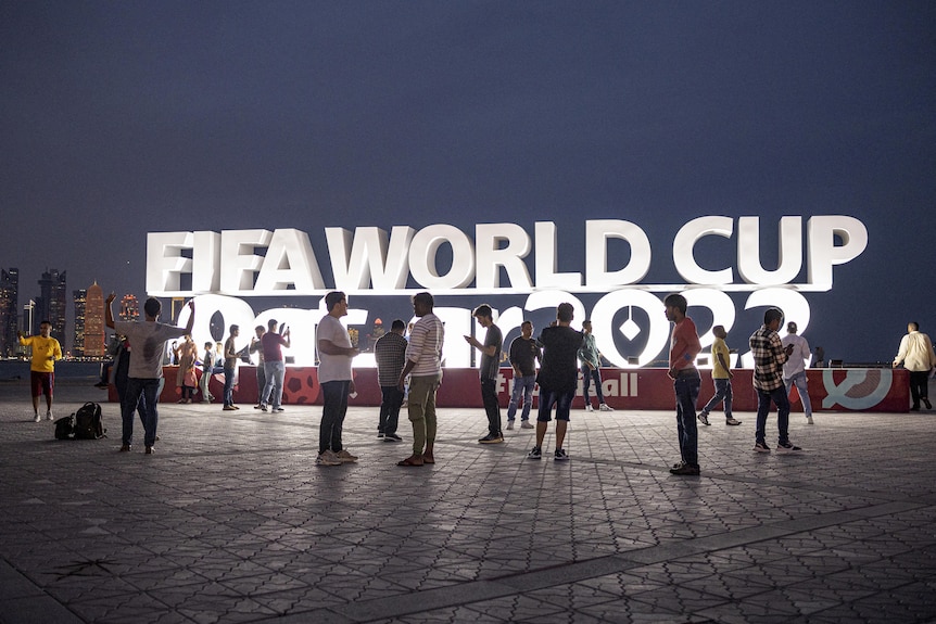 Le persone sono raffigurate davanti a un cartello della Coppa del mondo FIFA Qatar 2022 prima della Coppa del mondo.