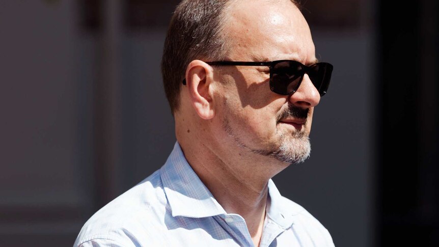 A headshot of Paul Yovich in a white shirt wearing sunglasses.