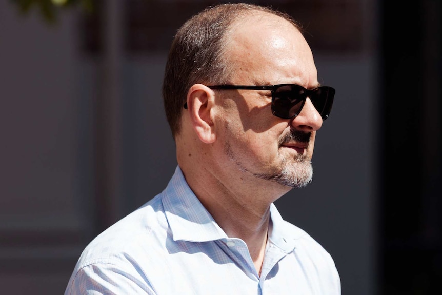 A headshot of Paul Yovich in a white shirt wearing sunglasses.