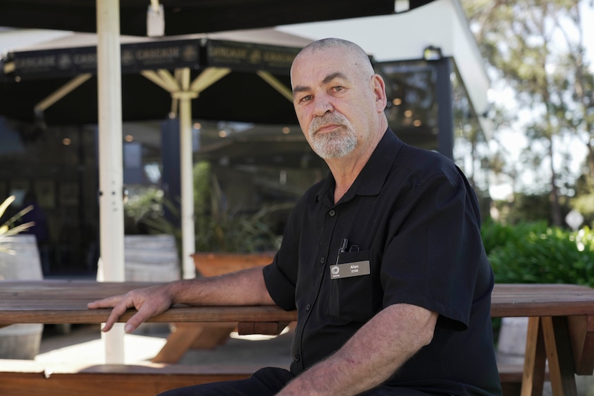 Publican Alan Burdon sits at a table at his pub in Orford, looking serious.