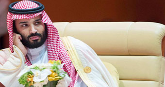 Crown Prince Mohammed bin Salman sit in a large creme leather chair.