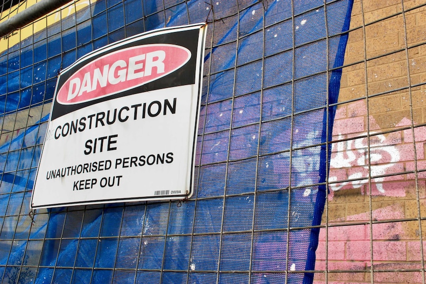 A construction site sign on a fence.