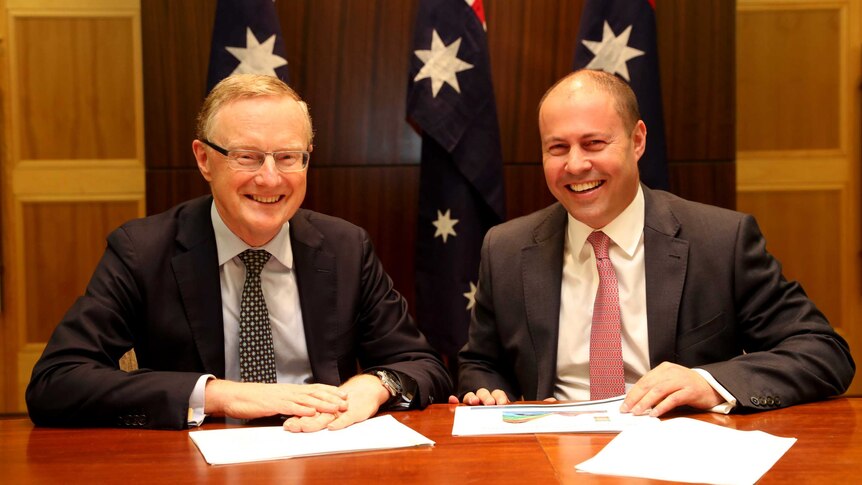 Philip Lowe and Josh Frydenberg sit at a table and smile.