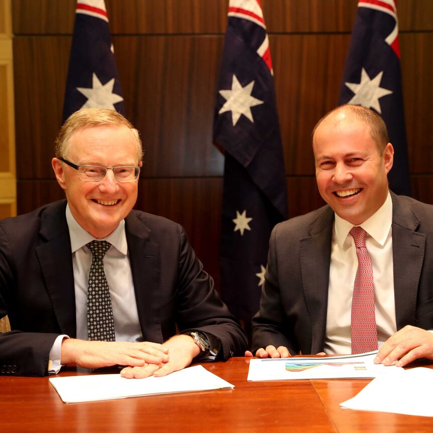 Philip Lowe and Josh Frydenberg sit at a table and smile.