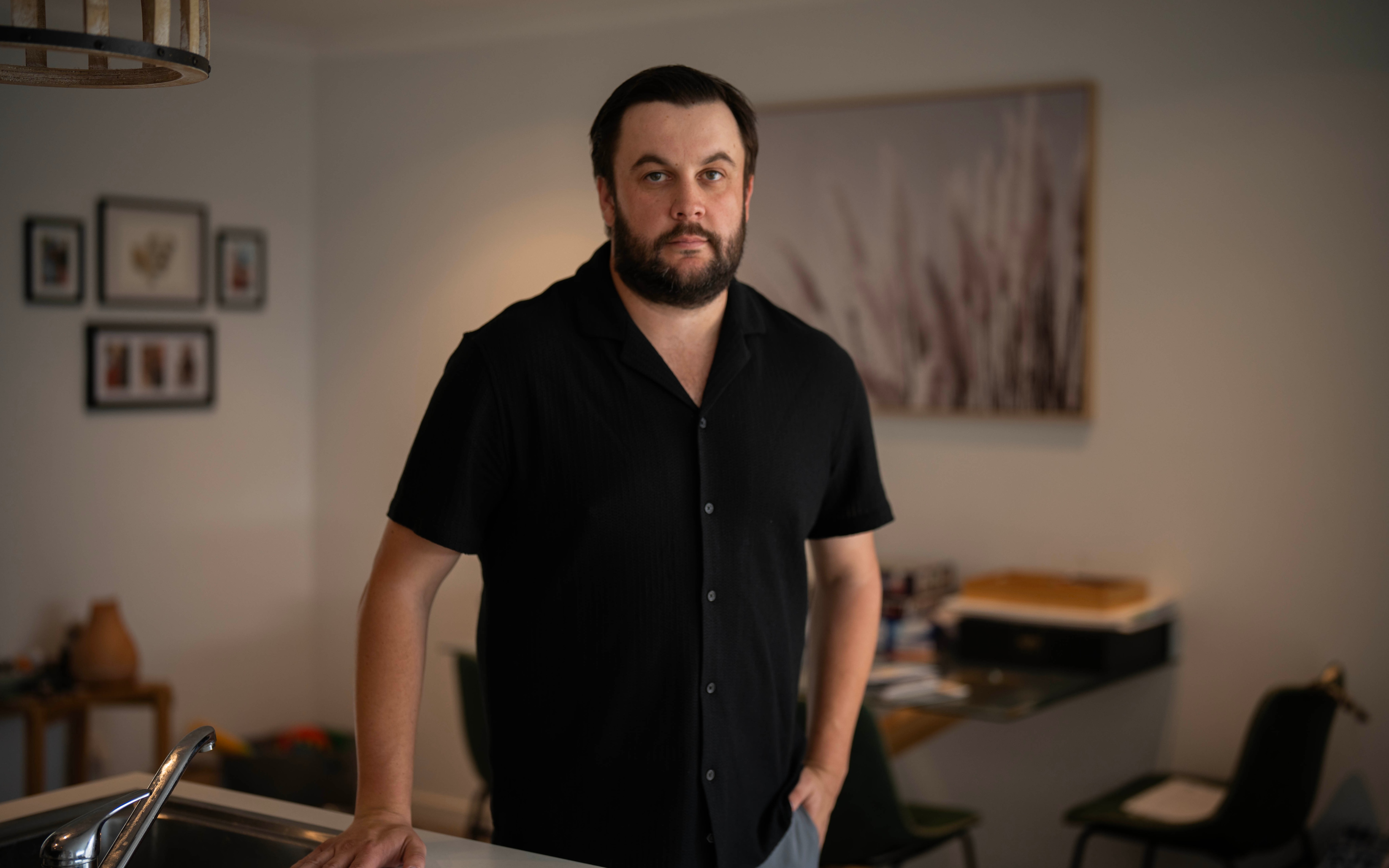 A man standing in his kitchen, looking at the camera.