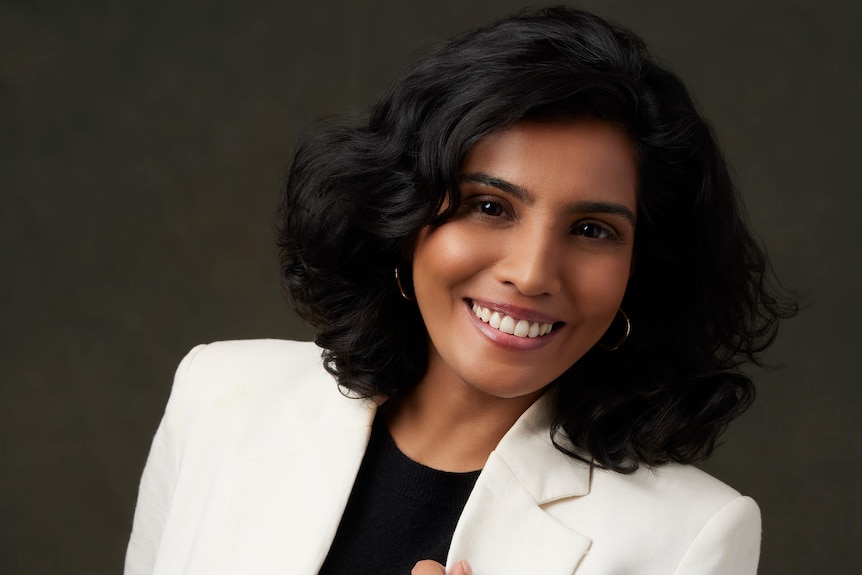 A woman wearing a black shirt and white suit jacket