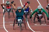 A wheelchair athlete raises her arms as she rolls over the finish line in Sydney's Olympic stadium.