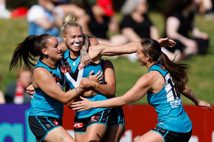 Port Adelaide AFLW captain Erin Phillips grins at her teammates as they hug her after a vital goal.