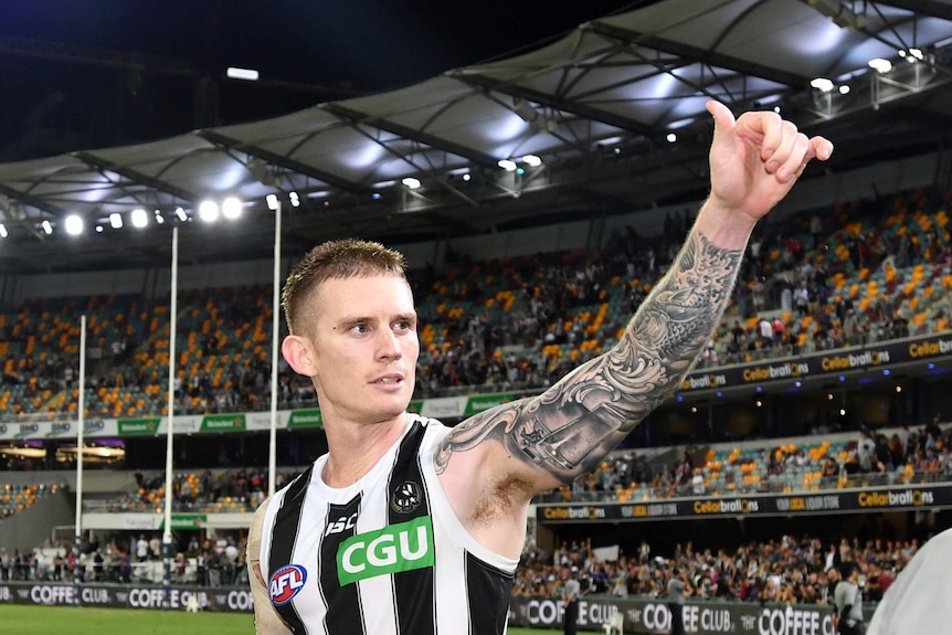 Dayne Beams holds his left hand up and looks out into the crowd after a Collingwood game.